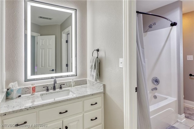 bathroom with baseboards, visible vents, a textured wall, vanity, and washtub / shower combination