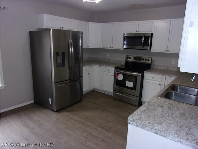 818 N 3rd St, Ozark, AR 72949 - kitchen featuring appliances with stainless steel finishes, white cabinets, wood finished floors, and light countertops
