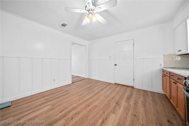 interior space featuring ceiling fan, ornamental molding, and light wood-type flooring