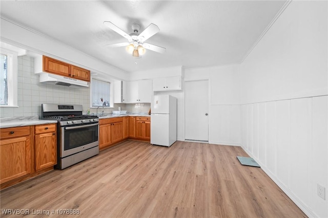 kitchen with stainless steel range with gas stovetop, light hardwood / wood-style floors, white fridge, and white cabinets