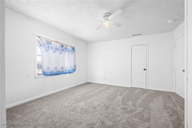 carpeted empty room with a textured ceiling and ceiling fan