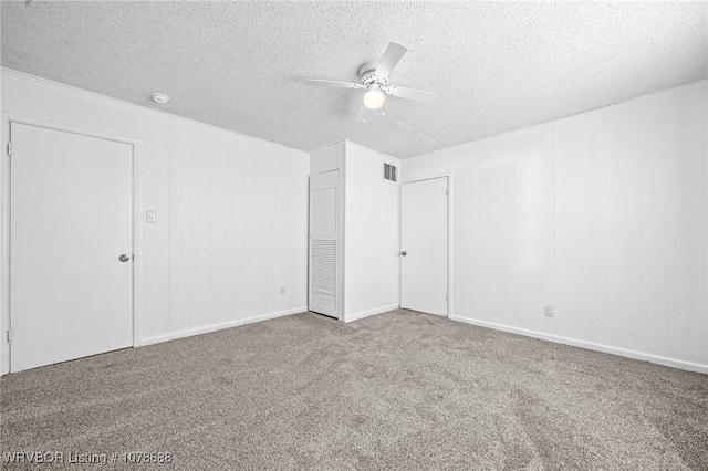 carpeted spare room featuring a textured ceiling and ceiling fan