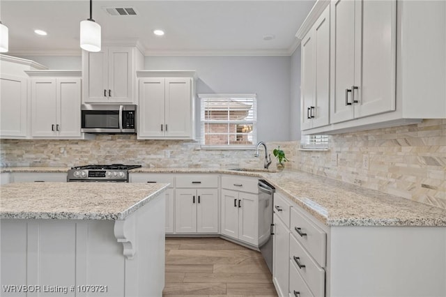 kitchen with white cabinetry, sink, stainless steel appliances, pendant lighting, and ornamental molding