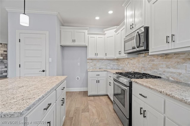 kitchen featuring backsplash, ornamental molding, stainless steel appliances, white cabinetry, and hanging light fixtures