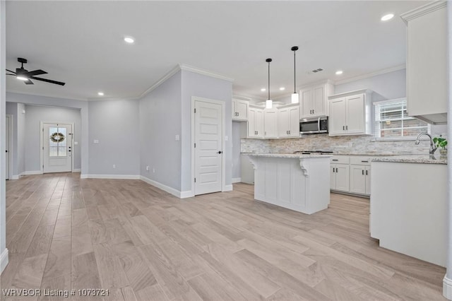 kitchen with ceiling fan, a center island, white cabinets, and light stone counters