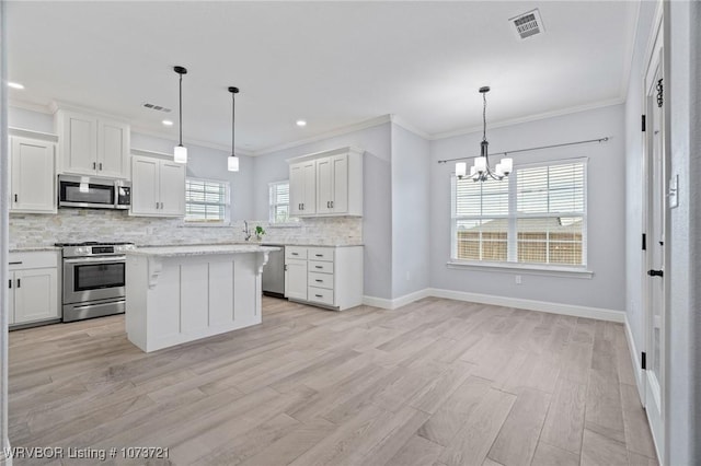 kitchen featuring appliances with stainless steel finishes, decorative light fixtures, and white cabinetry