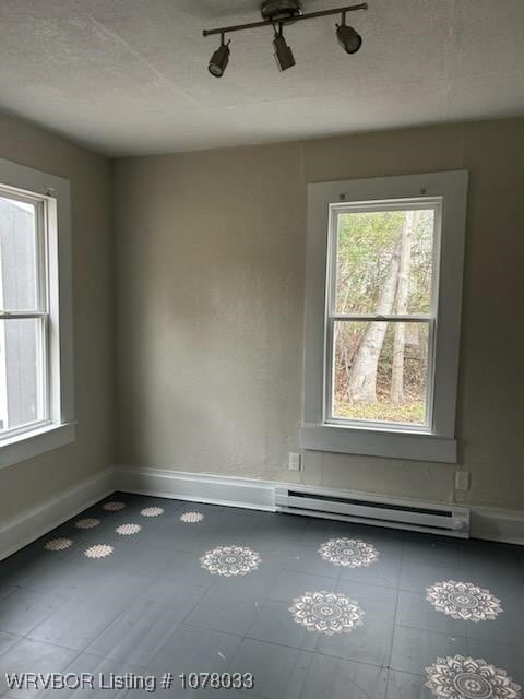 empty room featuring a baseboard radiator and track lighting