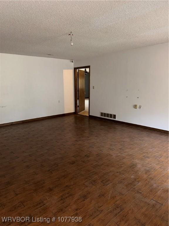 unfurnished room with a textured ceiling and dark wood-type flooring