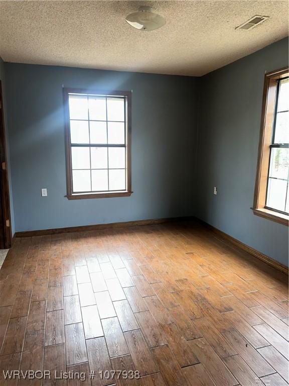 empty room featuring wood-type flooring and a textured ceiling