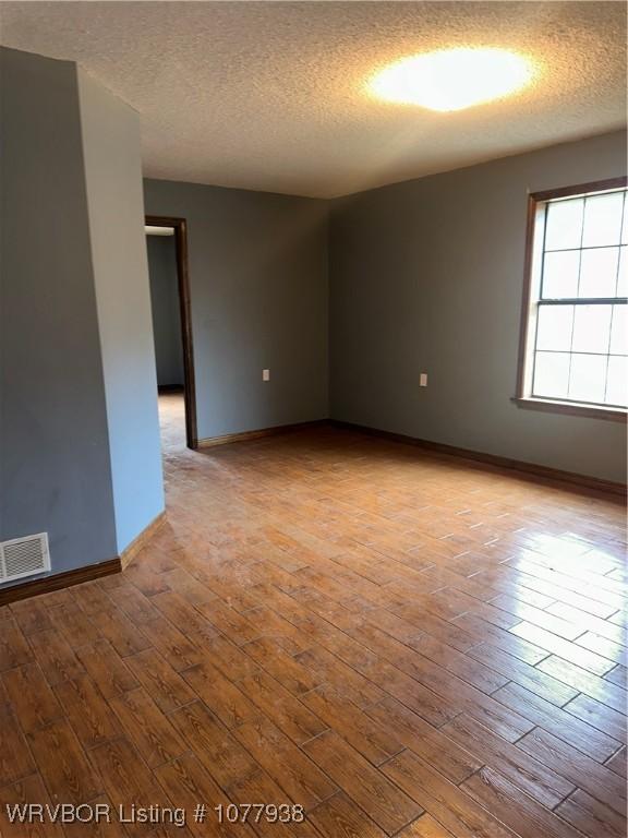 spare room with light wood-type flooring and a textured ceiling