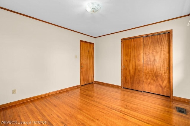 unfurnished bedroom with ornamental molding, light hardwood / wood-style floors, and a closet