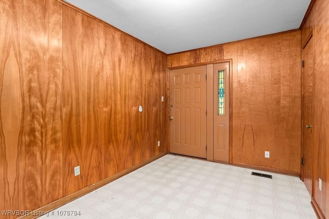 entrance foyer featuring ornamental molding and wooden walls