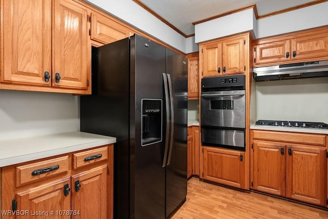 kitchen featuring ornamental molding, black fridge, stainless steel gas cooktop, and light hardwood / wood-style floors