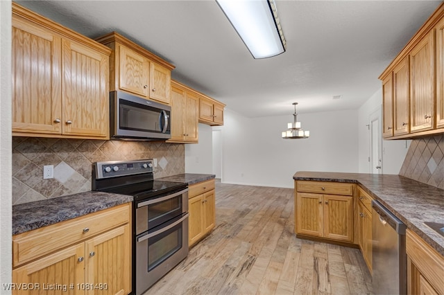 8601 Corona Ct, Uniontown, AR 72955 - kitchen with appliances with stainless steel finishes, dark countertops, a chandelier, light wood-style flooring, and a peninsula