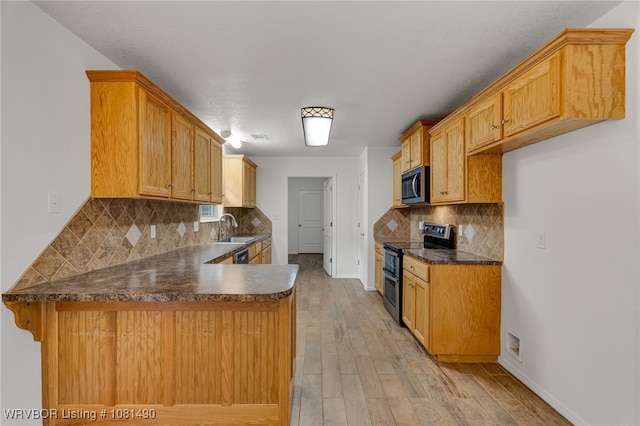 8601 Corona Ct, Uniontown, AR 72955 - kitchen with appliances with stainless steel finishes, a peninsula, dark countertops, backsplash, and light wood-style floors