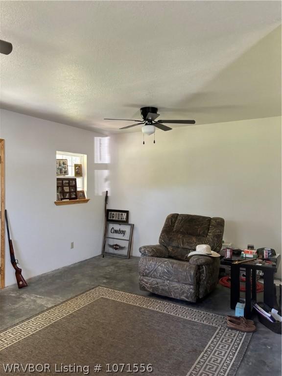 living area featuring ceiling fan and a textured ceiling