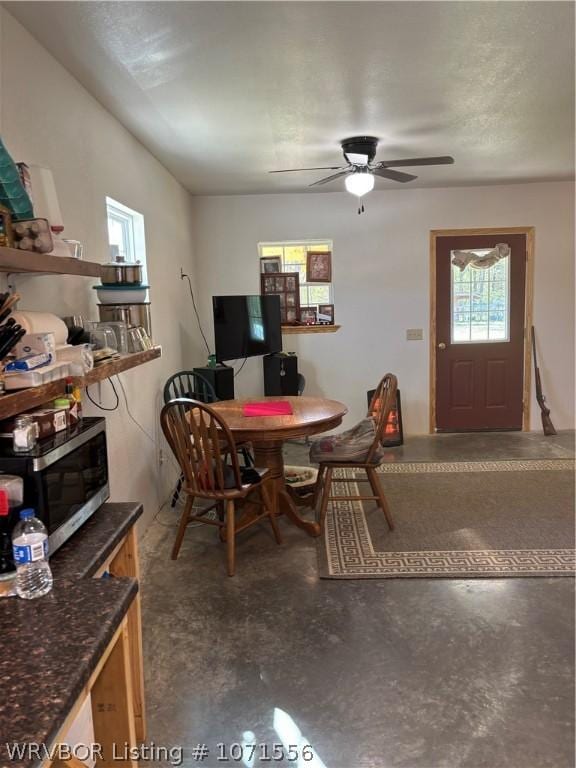 dining area with ceiling fan and concrete flooring