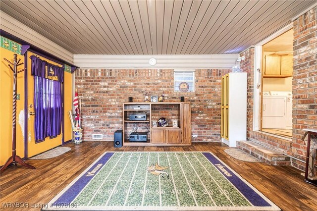 unfurnished living room with washing machine and clothes dryer, wood ceiling, dark wood-type flooring, and brick wall