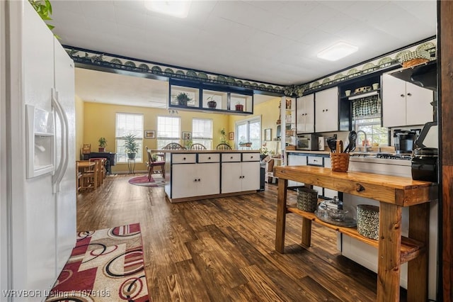 kitchen with dark hardwood / wood-style flooring, white fridge with ice dispenser, and white cabinets