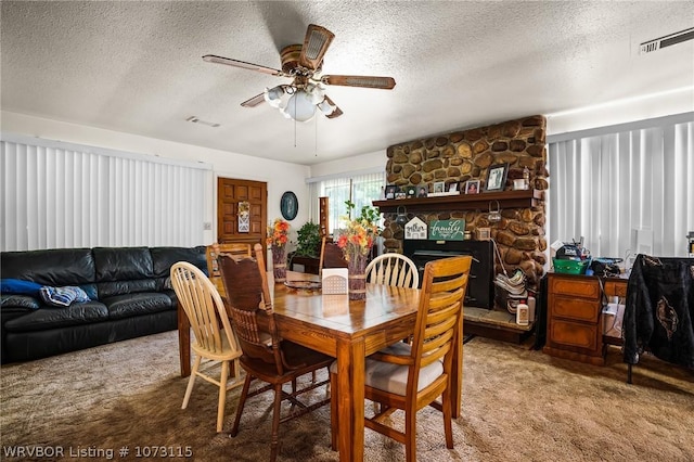 carpeted dining area featuring ceiling fan, a stone fireplace, and a textured ceiling