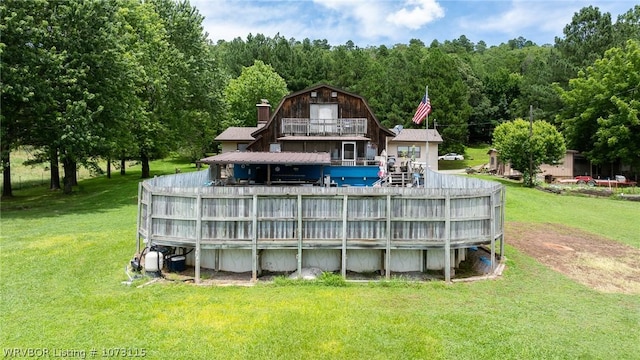 rear view of property featuring a yard and a balcony