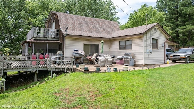 back of house featuring a lawn, a sunroom, and a balcony