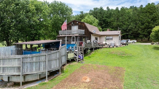 back of house featuring a balcony, a deck, and a lawn