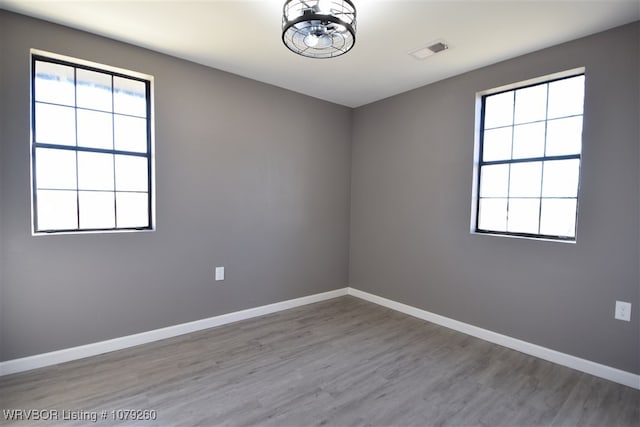 empty room with baseboards, visible vents, and wood finished floors