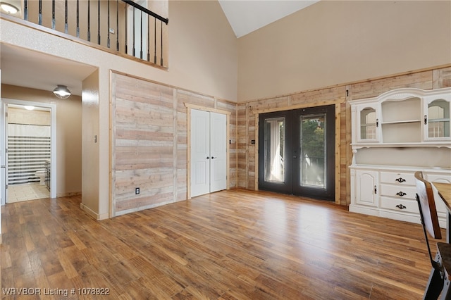 foyer entrance with hardwood / wood-style floors, high vaulted ceiling, and french doors