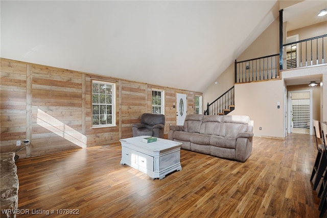 living room featuring wood-type flooring, high vaulted ceiling, and wood walls