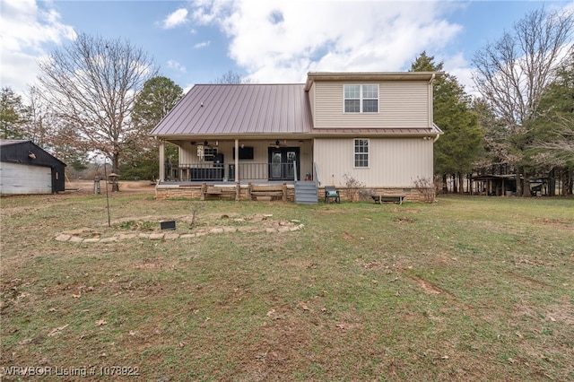 back of house featuring an outbuilding, a yard, covered porch, and a garage