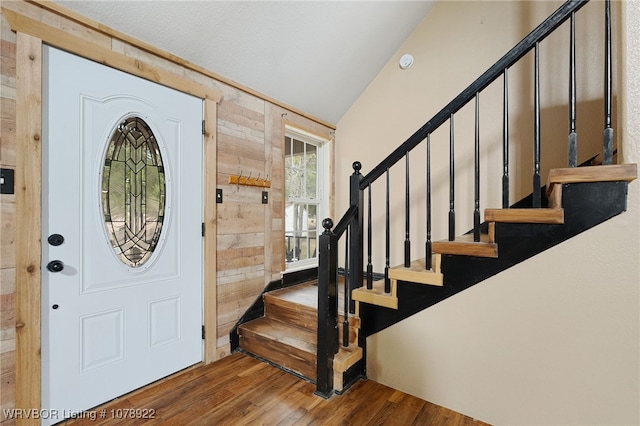 entrance foyer featuring lofted ceiling, dark wood-type flooring, and wood walls