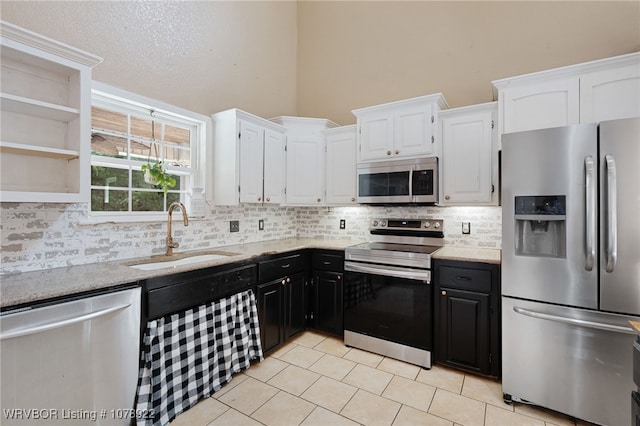 kitchen featuring sink, white cabinetry, stainless steel appliances, light stone countertops, and decorative backsplash