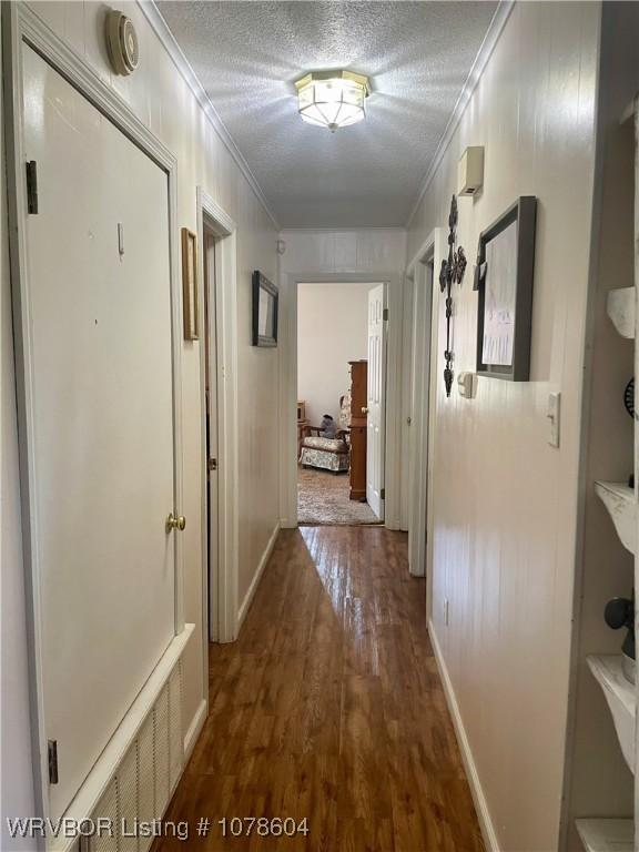 hall with crown molding, dark hardwood / wood-style floors, and a textured ceiling