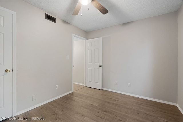 unfurnished bedroom with wood finished floors, baseboards, a textured ceiling, and a ceiling fan