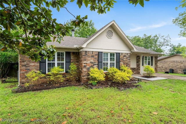 ranch-style home featuring a front yard, brick siding, and roof with shingles