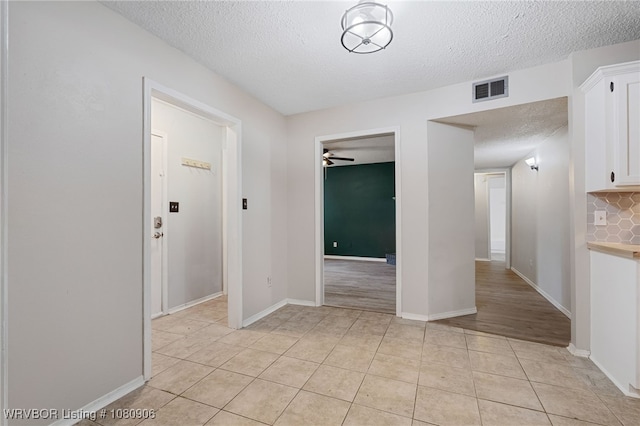 unfurnished room with a textured ceiling, a ceiling fan, and light tile patterned floors