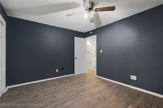 unfurnished room featuring wood finished floors, a textured ceiling, a ceiling fan, and baseboards