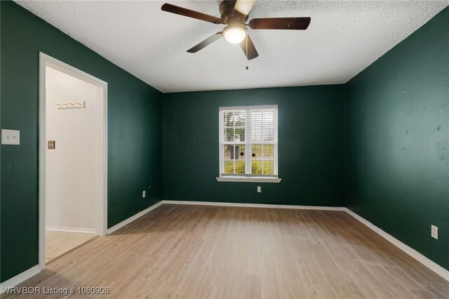 unfurnished room featuring wood finished floors, a ceiling fan, a textured ceiling, and baseboards