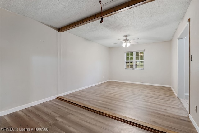 empty room featuring a textured ceiling, ceiling fan, wood finished floors, and baseboards