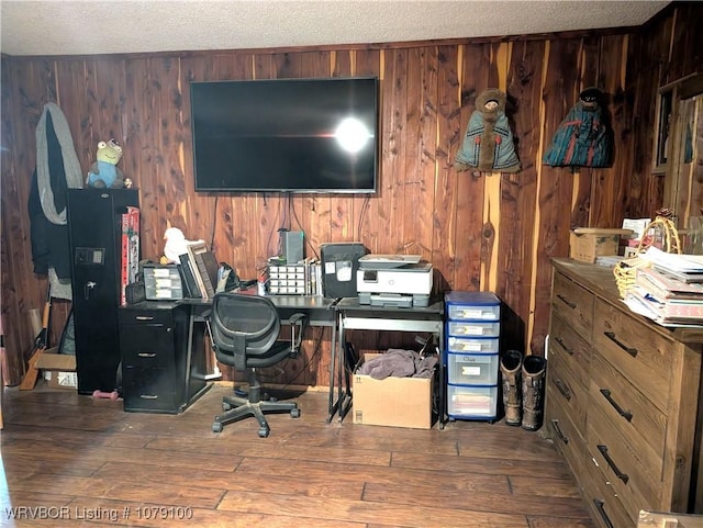 office space with wood walls, wood-type flooring, and a textured ceiling