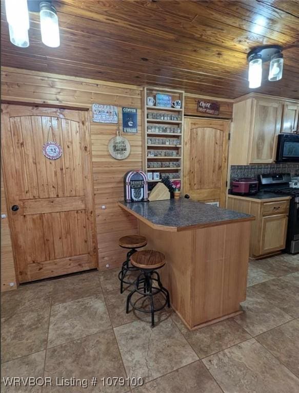 kitchen featuring range with gas stovetop, decorative backsplash, wood ceiling, a breakfast bar, and black microwave