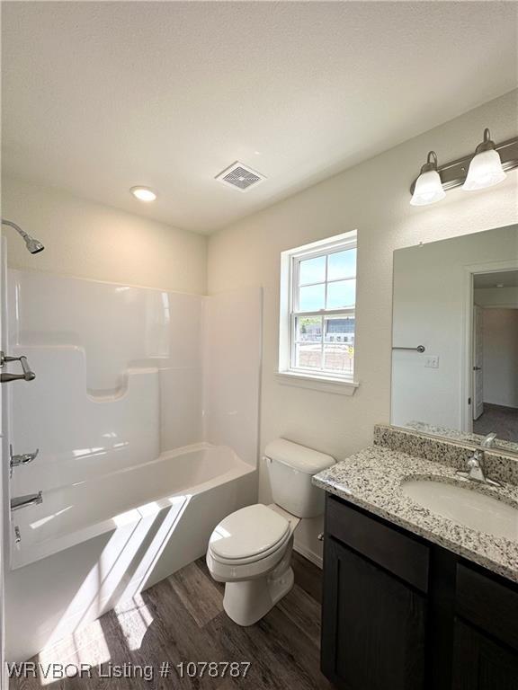 full bathroom featuring vanity, hardwood / wood-style flooring, toilet, and washtub / shower combination