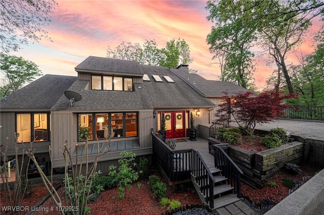 back of property with french doors, a shingled roof, and a chimney