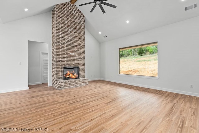 unfurnished living room featuring a fireplace, ceiling fan, high vaulted ceiling, beamed ceiling, and light hardwood / wood-style floors