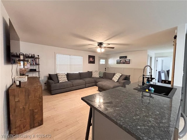 living room with ceiling fan, light wood-type flooring, and sink