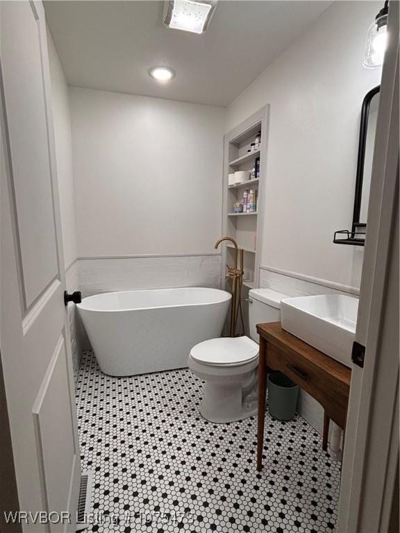 bathroom featuring built in features, tile patterned floors, toilet, a bathtub, and vanity