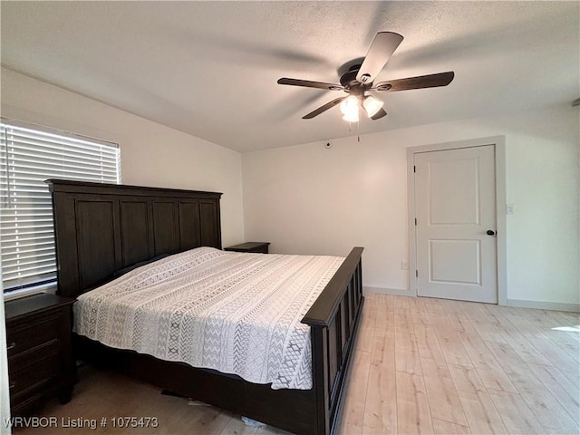 bedroom with ceiling fan, light hardwood / wood-style flooring, and a textured ceiling