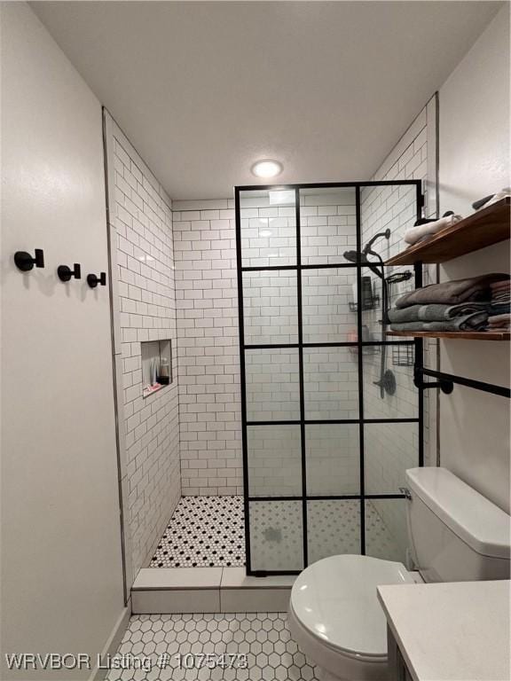 bathroom with tile patterned flooring, a tile shower, vanity, and toilet