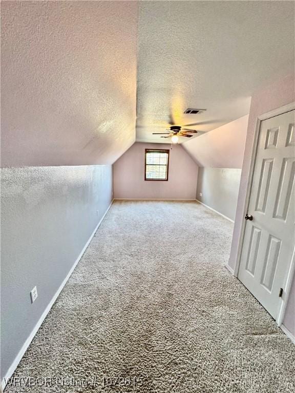 additional living space featuring lofted ceiling, carpet floors, a textured ceiling, and ceiling fan